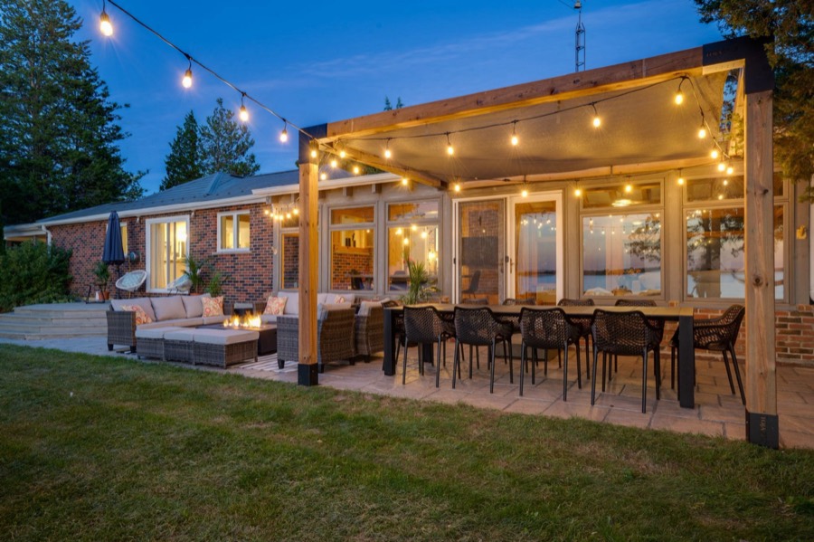 Pergola dining table for ten and lounge seating lit by string lights in the evening