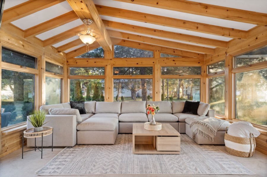 Sunroom sectional facing walls of windows and tall trees